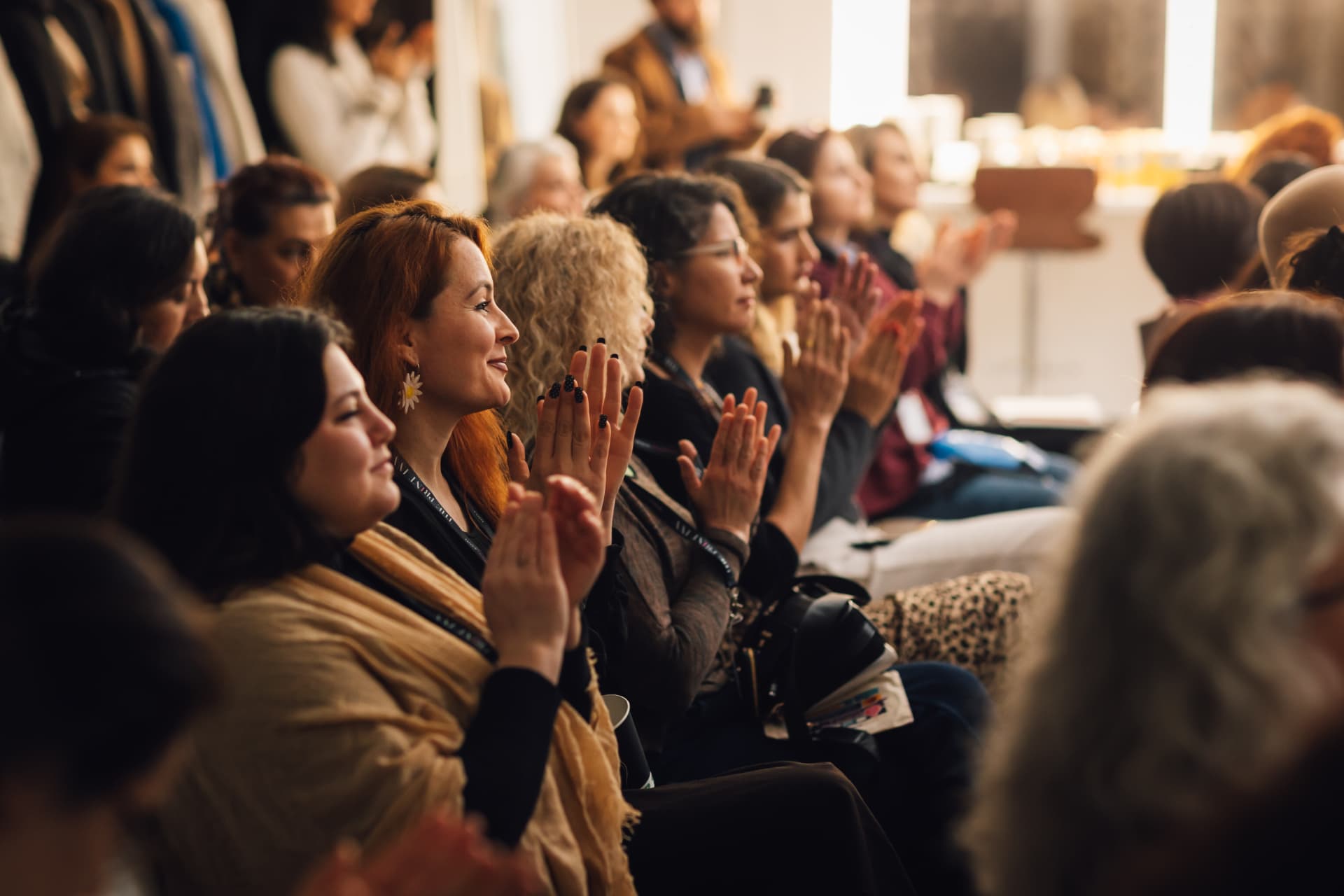 An audience applauding at a Rise Her Collective gathering